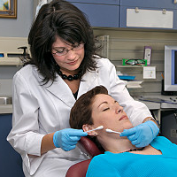Eine Ärztin trägt einer Patientin ein chemisches Peeling im Gesicht auf. 